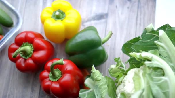Verse en kleurrijke paprika 's en andere groenten op houten tafel — Stockvideo