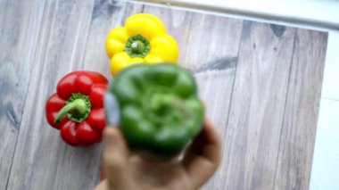 Ahşap bir masadan yeşil bir dolma biber alan bir kadın.