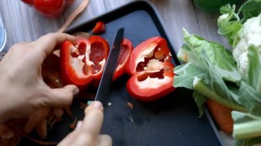 Kadın elleri tepside kırmızı bir dolma biberi sıkıca kesiyor.