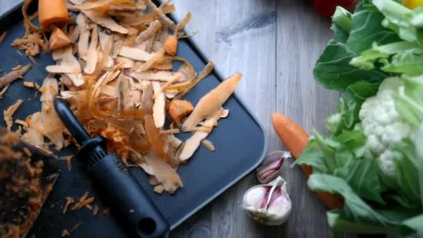 Подрібнену моркву в мисці поруч з морквою шкірку на столі — стокове відео