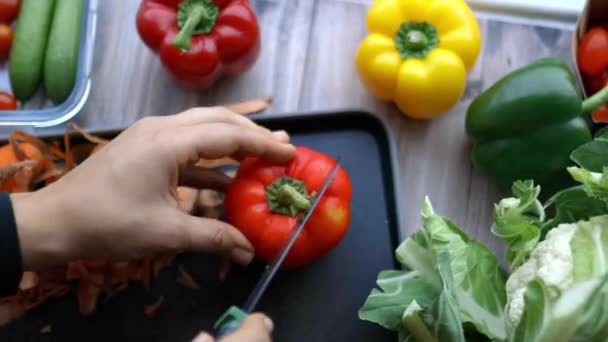 Vrouwelijke handen stevig snijden een rode paprika in de helft — Stockvideo