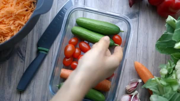 Vrouwelijke hand plukken komkommer uit een plastic container met groenten — Stockvideo