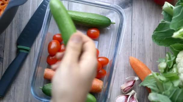 野菜の入ったプラスチック容器からキュウリを選ぶ女性の手 — ストック動画