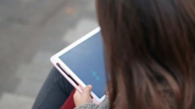 Mutlu küçük kız çizimlerini tablet üzerinde gösteriyor.