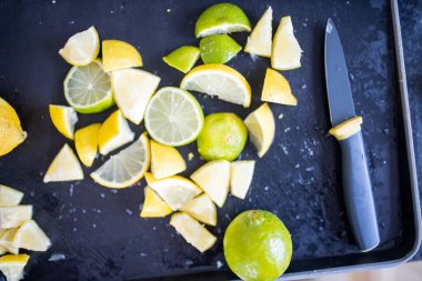 Limonlar ve limonlar siyah bir tepside dilimler.
