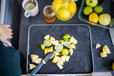 Siyah tepside limon ve limon dilimleyen kadın elleri.
