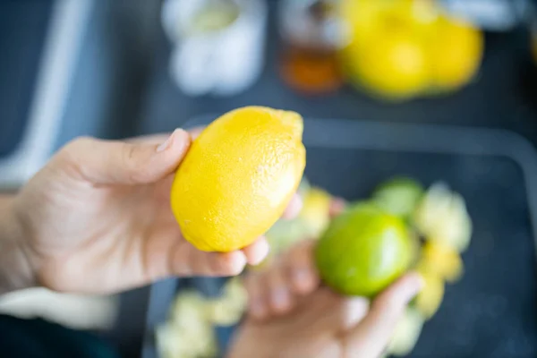 Female hands holding a lemon and a lime above fruit slices — Stock Photo, Image