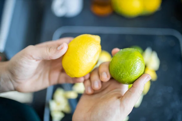 Female hands holding a lemon and a lime above fruit slices — Stock Photo, Image