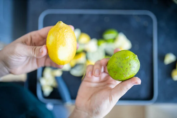 Female hands holding a lemon and a lime above fruit slices — Stock Photo, Image