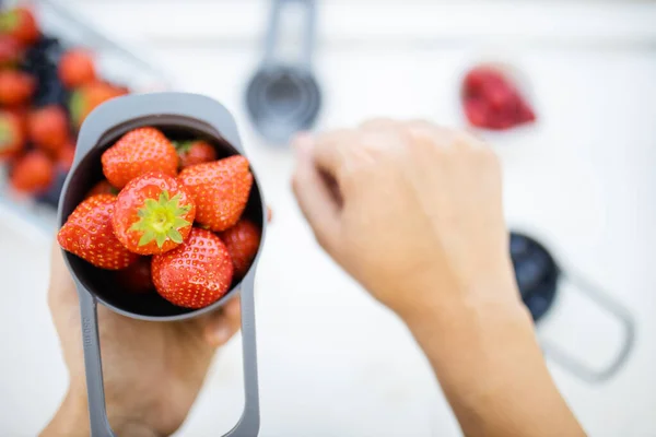 Manos femeninas sosteniendo taza medidora llena de fresas frescas —  Fotos de Stock