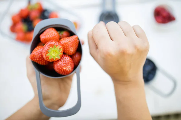 Manos femeninas sosteniendo taza medidora llena de fresas frescas — Foto de Stock