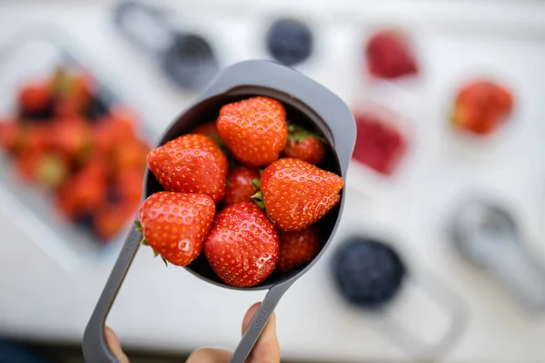 Taza medidora llena de fresas frescas sobre bayas en recipientes de plástico —  Fotos de Stock