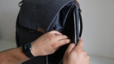 Erkek elleri gri bir sırt çantasının boş bölümlerini gösteriyor.