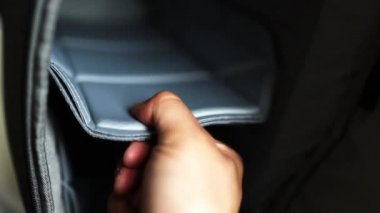 Erkek elleri gri bir sırt çantasının boş bölümlerini gösteriyor.