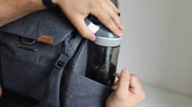 Erkek eller sırt çantasının yan bölümünde su şişesi taşıyor.