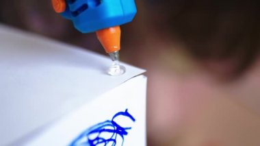 Yapıştırıcı tabancası beyaz bir kağıda yapıştırıcı ekliyor.