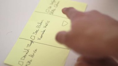 Masadaki küçük kız bir kağıt parçasına oy veriyormuş gibi yapıyor.