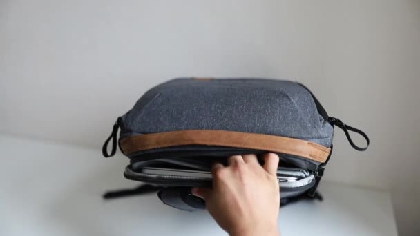 회색 가방의 뒷 칸에 있는 타블렛을 포장하는 남자 손 — 비디오