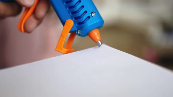 Клей пистолет добавляет горячий клей на белый лист бумаги — стоковое видео