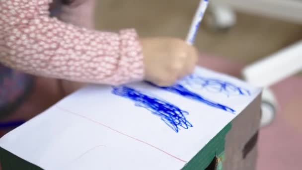 小女孩紧张地涂着一个带有蓝色记号的白色纸盒 — 图库视频影像