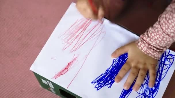 Liten flicka intensivt färga en vit papperslåda med en röd penna — Stockvideo