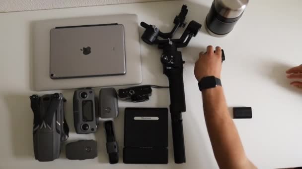 Mãos masculinas exibindo equipamentos de fotografia em uma mesa branca — Vídeo de Stock