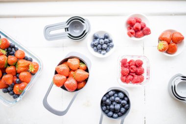 Yukardan gelen plastik kaplarda çilek, yabanmersini ve ahududu.