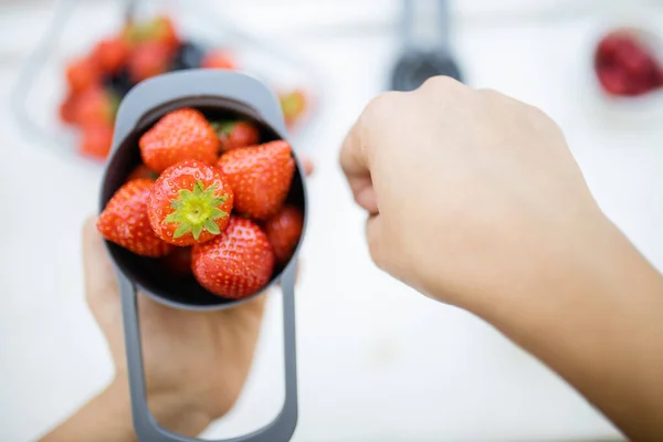 Manos femeninas sosteniendo taza medidora llena de fresas frescas — Foto de Stock