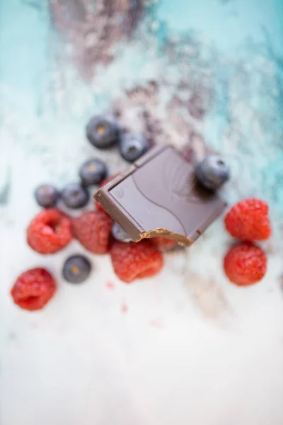 Bijten chocoladereep en bessen op een kleurrijke placemat — Stockfoto