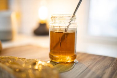 Bal kavanozu ve tahta masada fıstık ezmeli bir dilim ekmek.