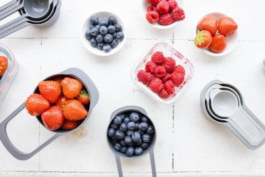 Yukardan gelen plastik kaplarda çilek, yabanmersini ve ahududu.