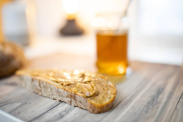 Tranche de pain au beurre d'arachide et pot de miel sur une table en bois — Photo