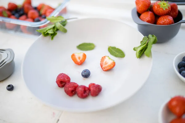 Leende ansikte gjort med bär och mynta blad på en tallrik — Stockfoto