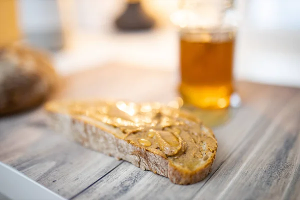 Fatia de pão com manteiga de amendoim e um pote de mel na mesa de madeira — Fotografia de Stock