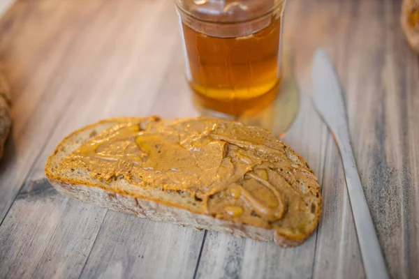 Tranche de pain au beurre d'arachide et pot de miel sur une table en bois — Photo