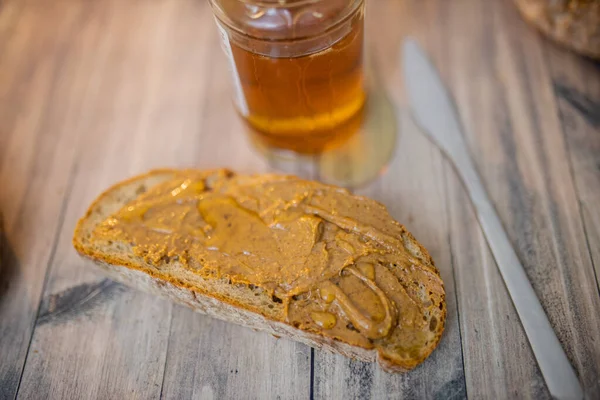 Tranche de pain au beurre d'arachide et pot de miel sur une table en bois — Photo