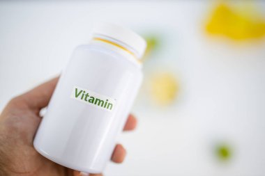 Elin limon ve limon dilimlerinin üzerinde bir şişe vitamin tutuyor.