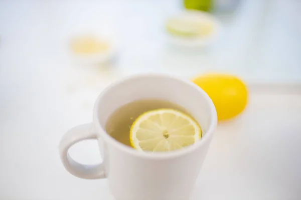Чашка лимонного чая на столе с лаймами и лимонами — стоковое фото