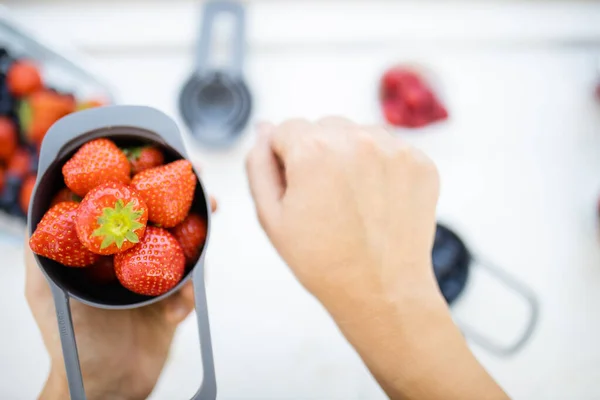 Manos femeninas sosteniendo taza medidora llena de fresas frescas —  Fotos de Stock