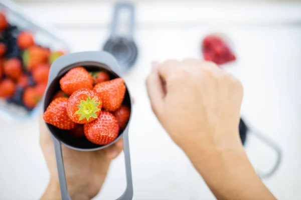 Manos femeninas sosteniendo taza medidora llena de fresas frescas —  Fotos de Stock