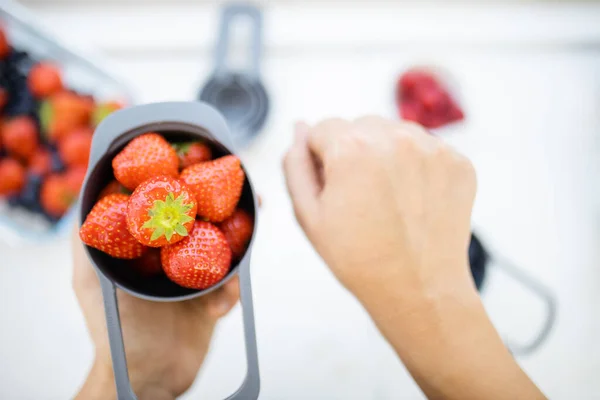 Manos femeninas sosteniendo taza medidora llena de fresas frescas —  Fotos de Stock