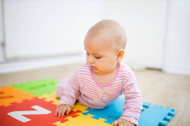 Sevimli bebek renkli bir paspasın üzerinde harflerle yatıyor.