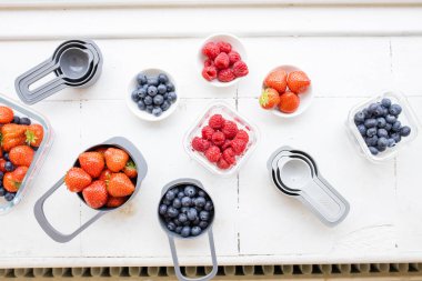 Yukardan gelen plastik kaplarda çilek, yabanmersini ve ahududu.
