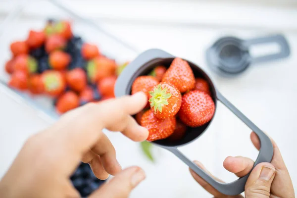 Manos femeninas sosteniendo taza medidora llena de fresas frescas — Foto de Stock