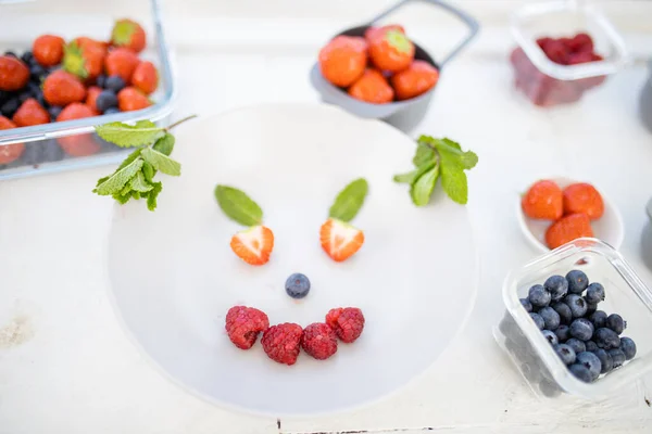 Glimlachend gezicht gemaakt met bessen en muntblaadjes op een bord — Stockfoto