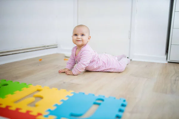 Schattige baby ligt gezicht naar beneden op de houten vloer — Stockfoto