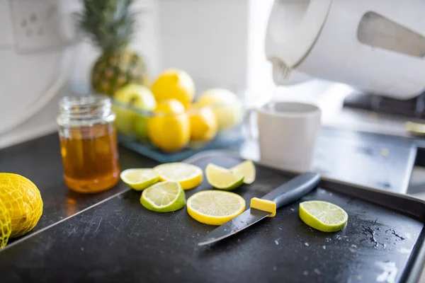 Lemon and lime slices on a tray next to a honey jar — Stock Photo, Image