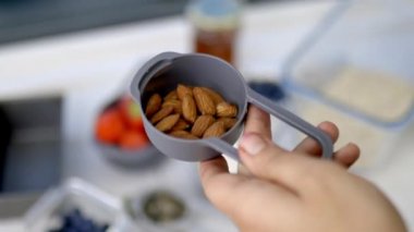 Plastik kaplarda taze bademlerle dolu bardakları ölçmek.