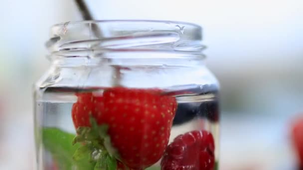 Stålhalm som rör om jordgubbar, blåbär och mintdryck — Stockvideo