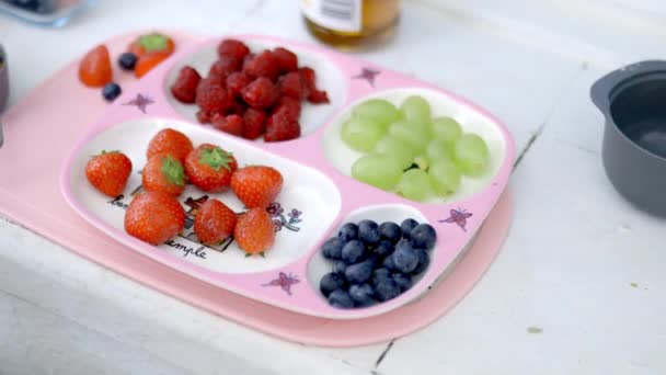 Bunte Beeren auf niedlichem rosa Tablett über der Küchentheke — Stockvideo
